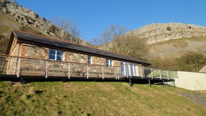 A stone building with a balcony, set against a mountainous backdrop.