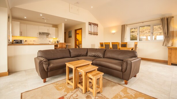 A modern living room with a brown leather sectional sofa, two wooden side tables, and a patterned rug.