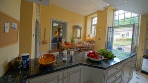 A kitchen with a granite countertop, white cabinets, and a view of the backyard through an open door.