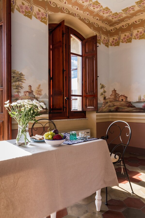 Un coin repas avec une table dressée pour deux personnes, un vase de fleurs et un tableau accroché au mur.