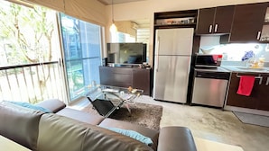 A modern kitchen with a refrigerator, microwave, and dishwasher. There is a dining table with chairs and a sofa in the living area. - Spacious 3-Level Loft: Functionality & Comfort for Long-Term Stays (Santa Ana)
