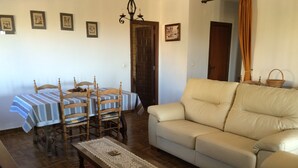 Un soggiorno con un divano, un tavolo da pranzo con sedie e un tappeto decorato.