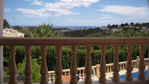 Un balcone con vista su un paesaggio costiero, che include case e vegetazione.