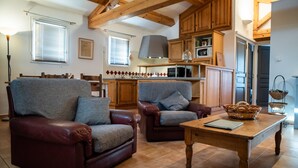 Un salon chaleureux avec deux canapés en cuir, une table basse en bois et un coin cuisine doté de meubles en bois et d’un four à micro-ondes.