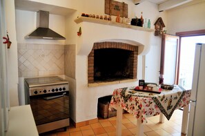 A kitchen with a stove, oven, and brick fireplace. - Tourist accommodation in the heart of Salento - Gallipoli Maldive del Salento Ugento (Casarano)