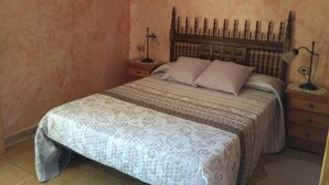 Une chambre à coucher avec un lit, deux tables de chevet, une tête de lit en bois et un tableau encadré au mur.