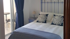 A bedroom with a bed, a chandelier, a nightstand, and a view of the outside. - Costa Calma Penthause. Wonderful penthouse On one of the best beaches in Europe (Pájara)
