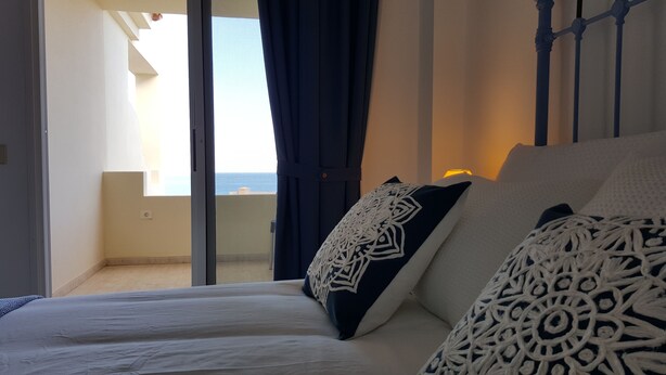 A bedroom with a bed, a view of the balcony, and a window with curtains. - Costa Calma Penthause. Wonderful penthouse On one of the best beaches in Europe (Pájara)