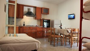 Ein kleines Hotelzimmer mit Küchenzeile, Essbereich und Bett.