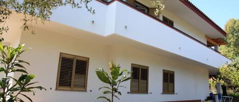 A two-story building with a white facade and red-tiled base.