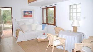 Un salon blanc avec un canapé, des fauteuils, une table et un tableau accroché au mur.