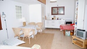 Un espace de vie compact comprenant un coin repas, une kitchenette et un téléviseur.