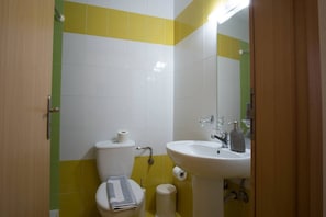 A small bathroom with a toilet, sink, and mirror.