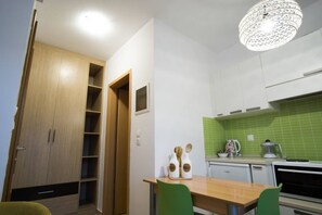 A compact kitchen with a dining area, a wooden door, and a green-tiled backsplash. - Urban Beach Sea (3C) (Rethymno)