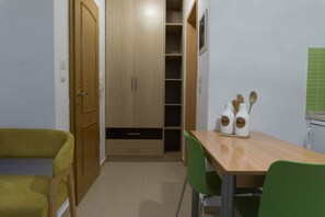 A compact room with a wooden wardrobe, a green chair, a wooden table, and a green tiled backsplash.