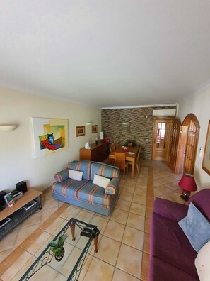 A living room with a sofa, a coffee table, and a dining area with a table and chairs.