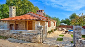 A stone house with a tiled roof, a chimney, and a small garden with outdoor seating. - Quiet and Cozy Cottage in Nature (Buje)