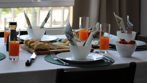 Een ontbijttafel met diverse gerechten, glazen sinaasappelsap en uitzicht uit het raam.