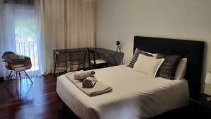 Een slaapkamer met een bed, bureau, stoel en lamp.