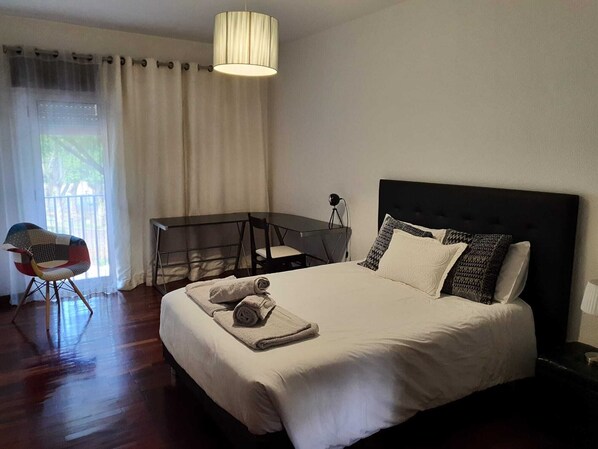 A bedroom with a bed, a desk, a chair, and a lamp. - Apartment near the beach for families up to 6 people (Machico)
