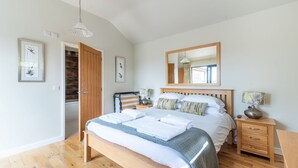 A bedroom with a wooden bed, a nightstand, a mirror, and a wardrobe.