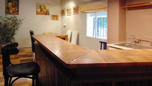 A dining area with a long wooden table, chairs, and a potted plant.