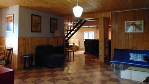 A spacious living area with a wooden floor, a staircase, and a blue sofa.