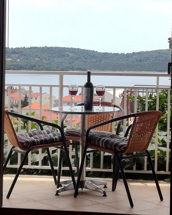 A balcony with a round table, two wicker chairs, and two wine glasses.