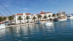 A marina with boats docked, palm trees, and historic buildings with red roofs. - 3 room apartment - cozy and modern (Trogir)
