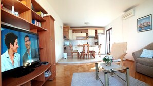 A living room with a television, a sofa, a coffee table, and a dining area with chairs and a table. - 3 room apartment - cozy and modern (Trogir)