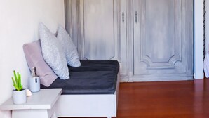 A bedroom with a bed, a small table with a plant, and a wardrobe. - Azenhas Beach Room - Azehas do Mar (Lisboa)