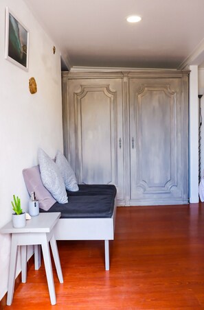 A bedroom with a bed, a small table with a plant, and a wardrobe. - Azenhas Beach Room - Azehas do Mar (Lisboa)