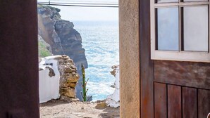 A stone pathway leading to a coastal view with a wooden door and window. - Azenhas Beach Room - Azehas do Mar (Lisboa)