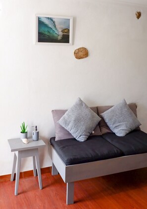 Een moderne slaapkamer met een bed, een klein tafeltje met een plant en een ingelijst beeld aan de muur.