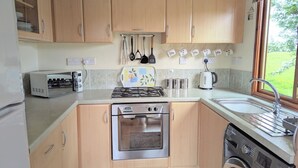 A compact kitchen with a gas stove, built-in oven, toaster, and washing machine.