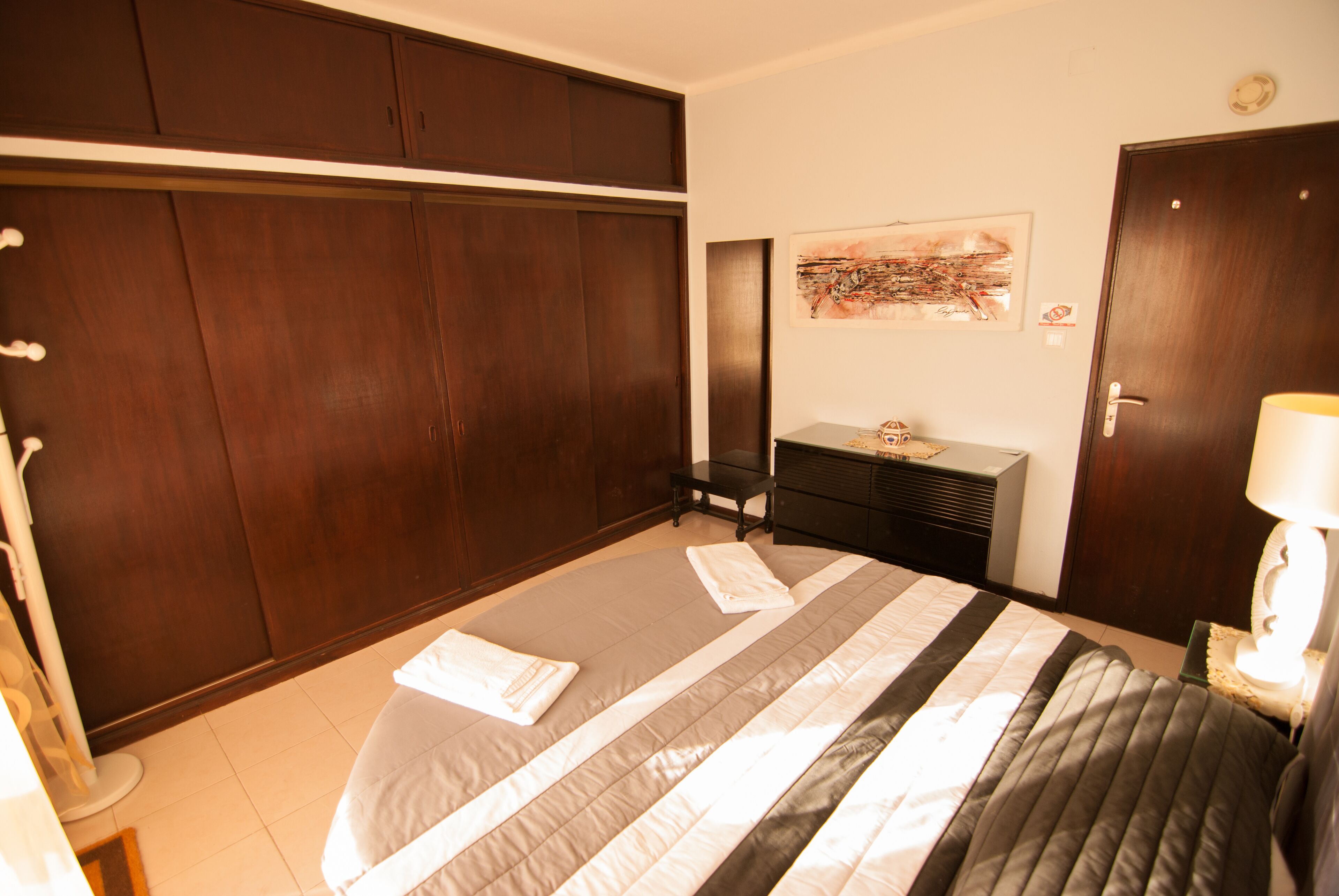 Ein Schlafzimmer mit einem großen Bett, einem Kleiderschrank, einer Kommode und einem Gemälde an der Wand.