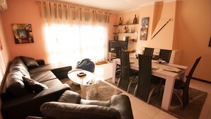 Ein Wohnzimmer mit einer Couch, einem Glastisch und einem Essbereich mit Tisch und Stühlen.