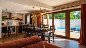 A modern kitchen with a dining area, a poolside view, and a cozy living space. - Villa Miandri with heated pool (Debeljak)
