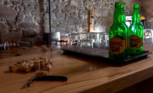 A bar area with green bottles labeled 'Tabanco', a tray with glasses, and a pile of corks on a wooden counter.