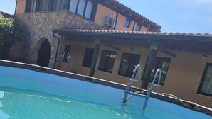 A swimming pool with a stone wall and a building in the background. - Fantastic rural house "Amaltea" in Candeleda (Candeleda)