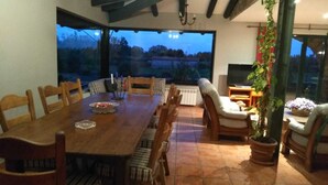 A dining area with a wooden table and chairs, a TV, and a large window with a view of the outdoors. - Fantastic rural house "Amaltea" in Candeleda (Candeleda)