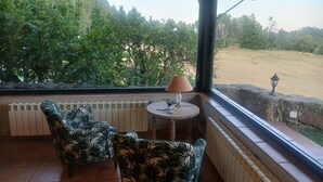 A covered patio with two chairs, a table with a lamp, and a view of a field with trees. - Fantastic rural house "Amaltea" in Candeleda (Candeleda)