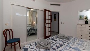 Ein Schlafzimmer mit Bett, Stuhl, Kommode und Deckenventilator.