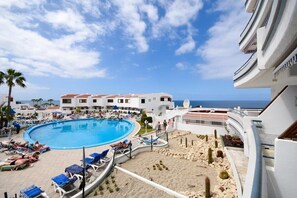 A resort with a large pool, sun loungers, and a view of the sea. - Club Atlantis 35 - One Bed with pool and sea view (Adeje)