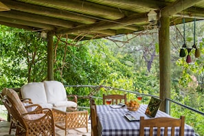 A covered outdoor seating area with wicker furniture and a checkered tablecloth.