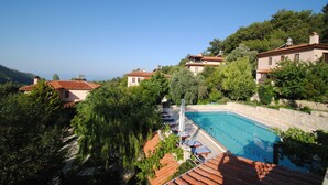 A pool area with lounge chairs and a clear view of the surrounding hillside.