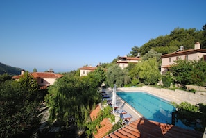A pool area with lounge chairs and a clear view of the surrounding hillside.