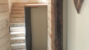 Un escalier en bois menant à une mezzanine caractérisée par des poutres apparentes et une esthétique rustique.