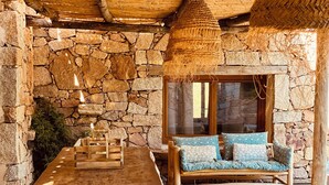 Une terrasse en bois rustique, avec un mur en pierre et un plafond fait de lattes entrelacées.