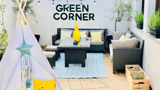A cozy outdoor seating area with a sofa, a coffee table, and a small table with a yellow vase. There is a teepee with the word "SMILE" on it, and a sign that reads "GREEN CORNER". - BEAUTIFUL DESIGN FLOOR IN THE CENTER OF AVILA FOR 6 PEOPLE (Ávila)